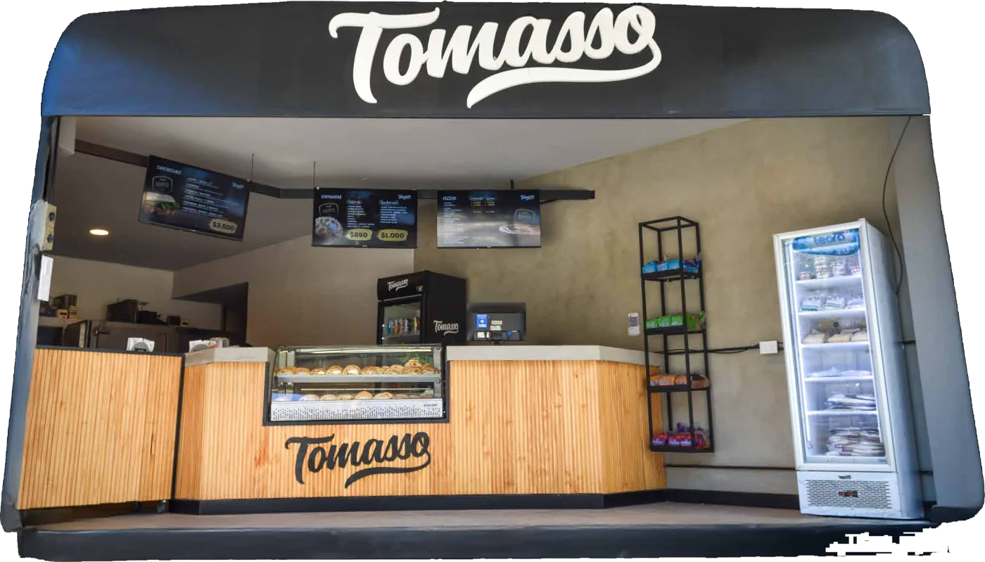 Local franquiciado Tomasso de pizzas y empanadas con mostrador de madera, exhibidora de empanadas y menú digital