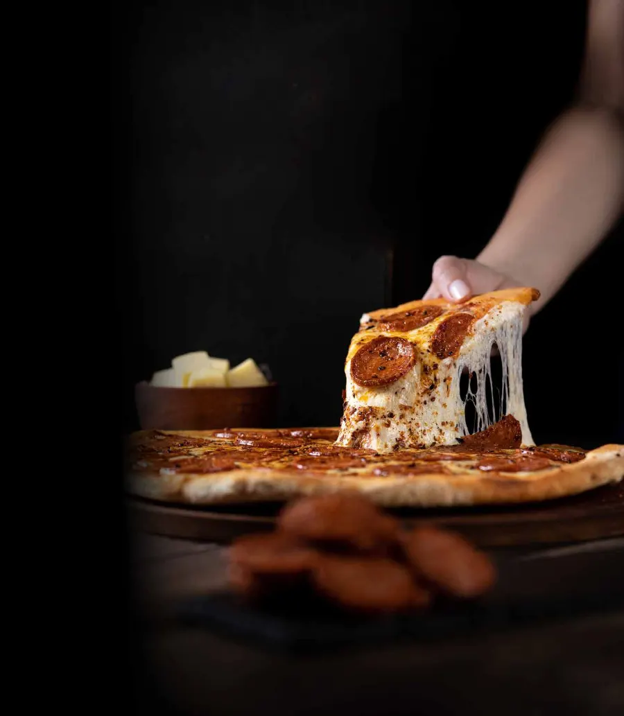 Porción de pizza de pepperoni con muzzarella derretida de Tomasso
